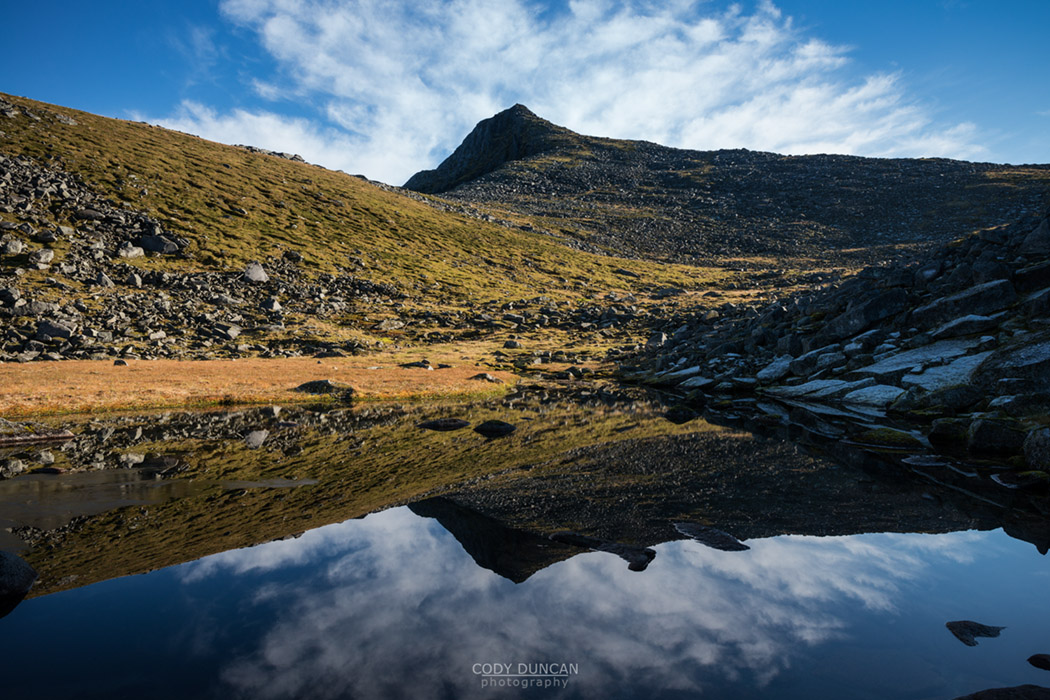 Kroktind (707m) mountain peak reflects in small lake, Austvagoy, Lofoten Islands, Norway