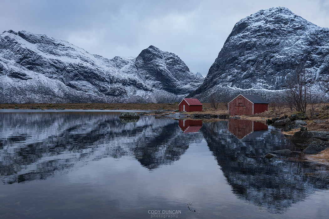 Boat sheds and mountains reflection on Selfjord in winter, Moskenesøy, Lofoten Islands, Norway