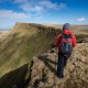 Female hill walker hiking on Carmarthen Fans - Bannau Sir Gaer with Picws Du in distance, Black Mountain, Brecon Beacons national park, Wales