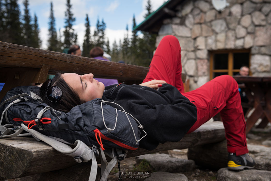 Female hiker sleeps on bench outside Murowaniec hut, Tatra mountains, Poland