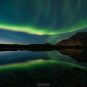 Reflection of northern lights in sky over mountains of Flakstadøy, Lofoten Islands, Norway